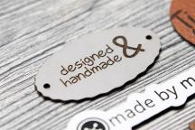 Vaalea keinonahkaetiketti tekstillä 'designed & handmade' - Nimikenumero 3003
