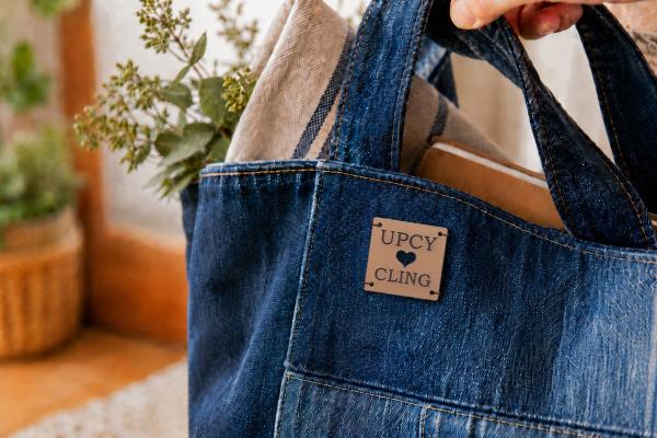 Vaaleanruskea neliömäinen kaktusnahkamerkki, "UPCYCLING" ja stanssattu sydän farkkukassissa.